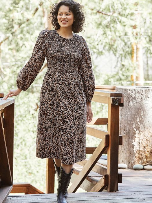 A model wearing a black and brown patterned dress with black cowboy boots.