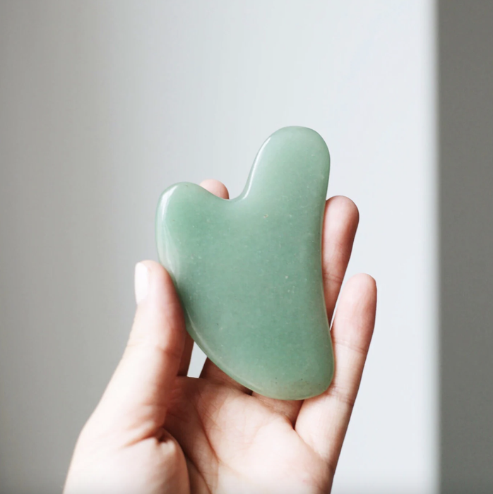 A model holding the jade Gua Sha in their hand.