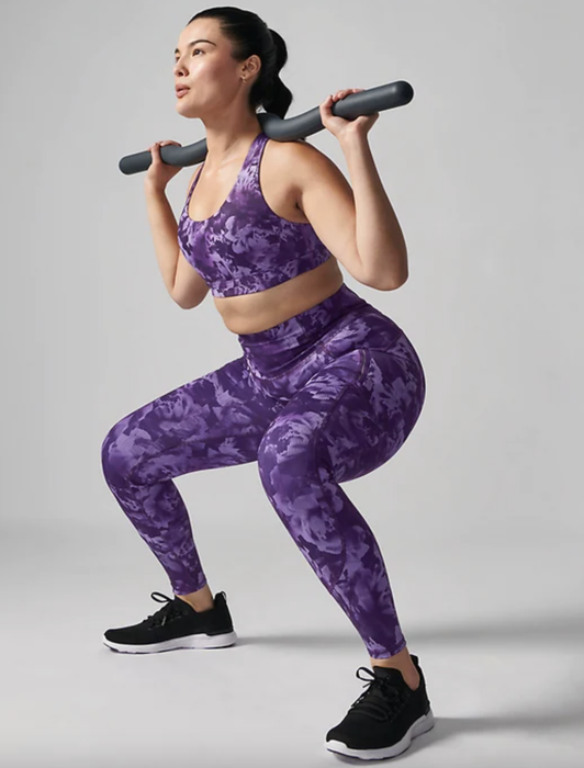 A model demonstrates the tights while performing a weighted squat.