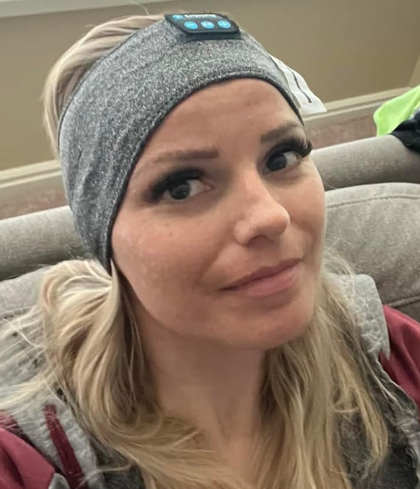 A reviewer wearing a gray headband with built-in speaker headphones.