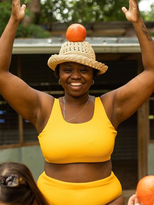 A plus-size model confidently wearing the mango-colored scoop top.