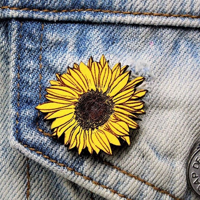 A sunflower-shaped pin attached to a denim jacket