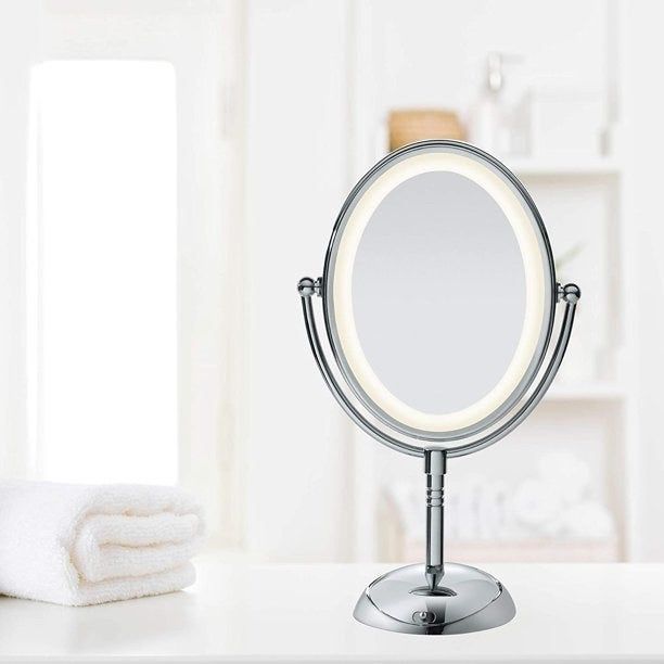 Oval-shaped silver mirror with an LED light border sitting on a bathroom counter