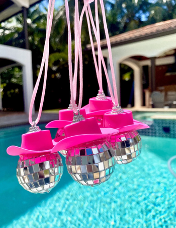 Tiny disco balls with pink cowboy hats hanging from a string