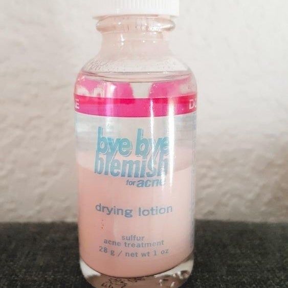 A lotion bottle with a pink base and a clear top, which you dip through to reach the pink liquid inside.