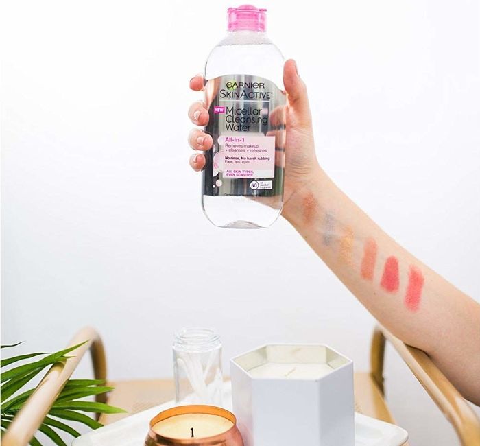 A hand gripping a bottle of micellar water.