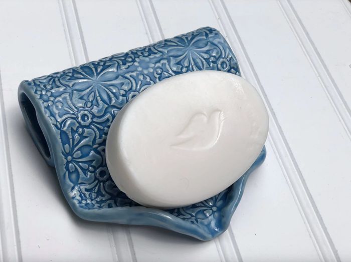 A blue patterned ceramic dish featuring a fold for proper drainage, adding both functionality and style to your bathroom.