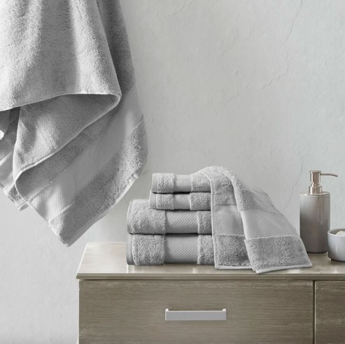 Grey towels neatly stacked on a counter, with one draped gracefully behind.