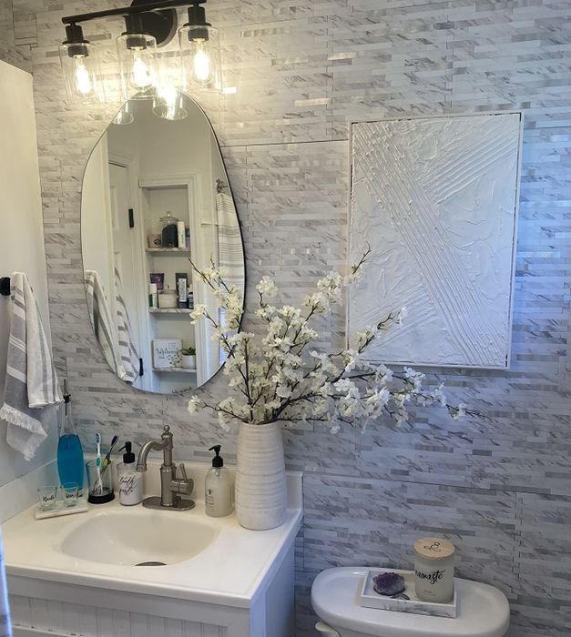 a reviewer's snapshot of a sleek black light fixture enhancing the ambiance of a white and grey themed bathroom