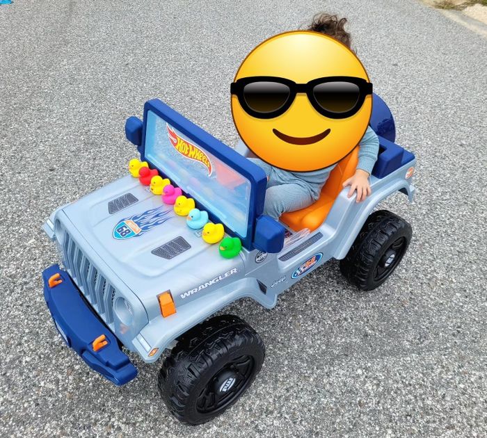 A child enjoying a ride in a battery-powered Hot Wheels Jeep