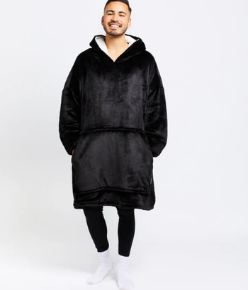A model showcasing a black oversized hoodie blanket