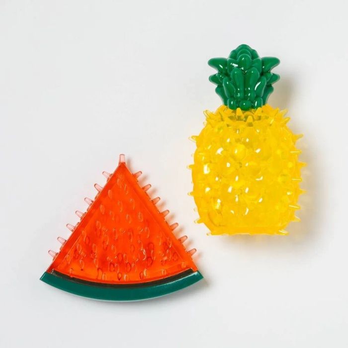A set of plastic toys, one designed as a watermelon slice and the other as a pineapple, both made to hold treats and cool your pet down.