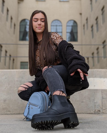 A reviewer wearing sleek ankle boots with rubber-heeled soles.