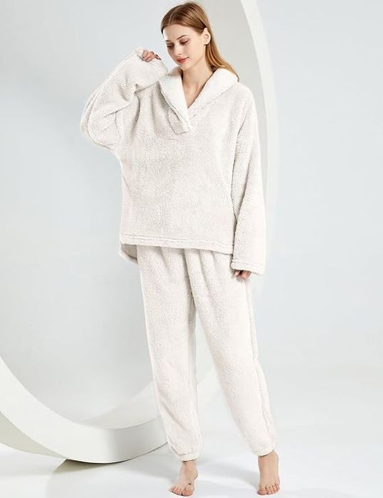 A person modeling an oversized fleece loungewear set with a hood, standing barefoot
