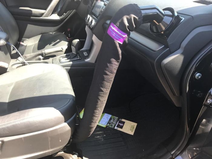 The interior of a car with a sun shield covering the steering wheel and pamphlets scattered across the driver's side floor.