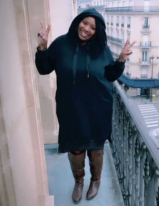A reviewer modeling the knee-length hoodie dress in classic black