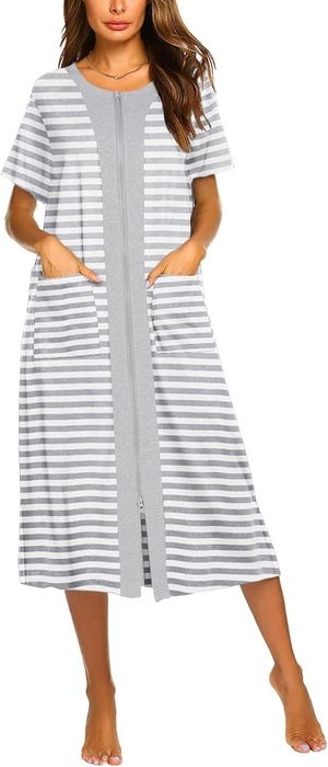 A person sporting a short-sleeved, striped lounge dress that zips up, equipped with pockets, and standing without footwear