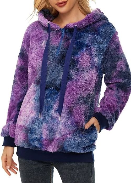 A person dressed in a soft, textured hoodie featuring a tie-dye design, oversized drawstrings, and front pockets, styled with jeans