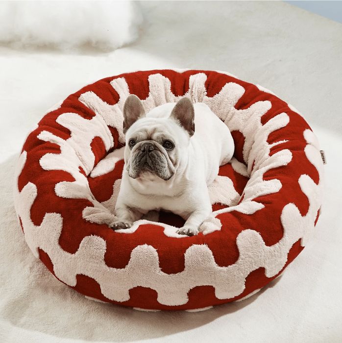 A French Bulldog lounges in a round, ultra-soft pet bed with eye-catching, bold wavy patterns.