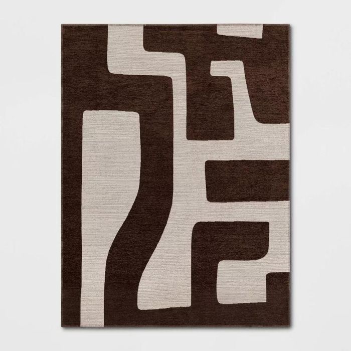 A dark brown and cream rug featuring a large, abstract pattern