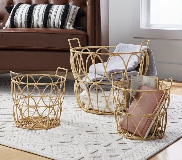 The smaller baskets placed in front of the larger one, with one holding blankets and the other filled with newspapers and a journal.