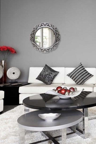The silver-framed mirror hanging on the wall behind the couch.