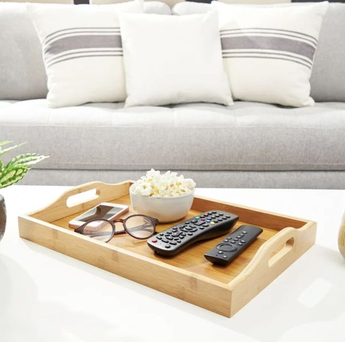The tray styled with popcorn, remotes, glasses, and a phone.