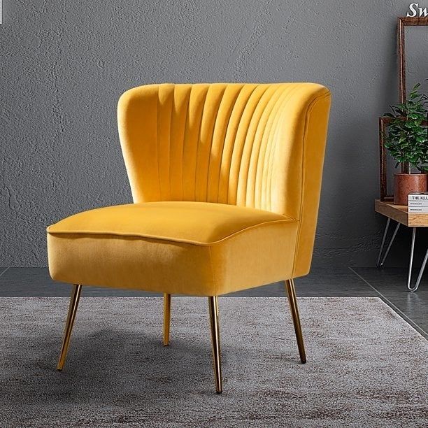 The bright yellow velvet chair placed on a cozy rug.