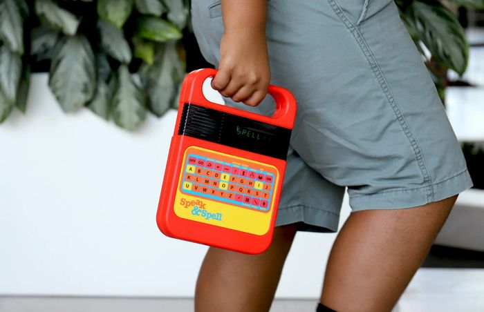 A child holding a Speak & Spell educational toy, crafted to enhance spelling and language skills