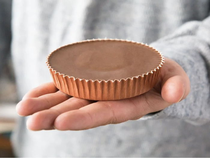 a model displays a jumbo peanut butter cup that matches the size of their palm