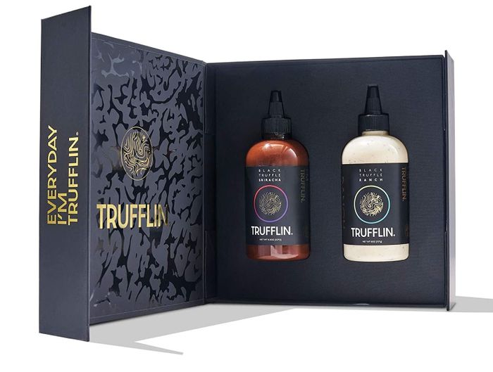Two squeeze bottles of sauce presented in a sleek black and gold gift box.