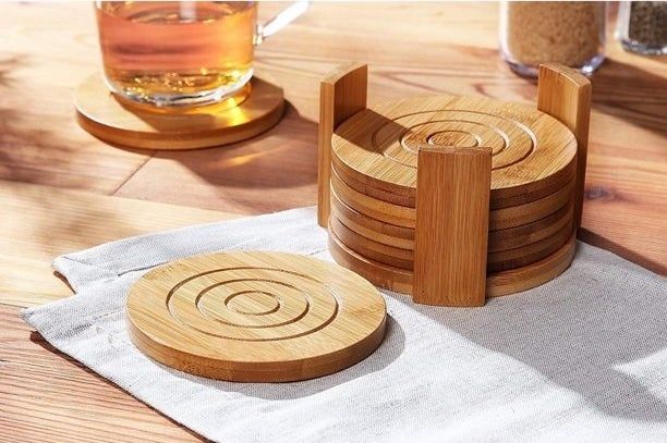 Four bamboo coasters arranged in a holder, with one coaster supporting a drink and another resting on a napkin.