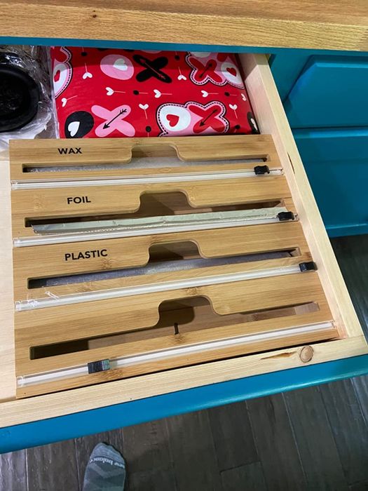 The organizer neatly holds wax paper, foil, and plastic wrap within a drawer.