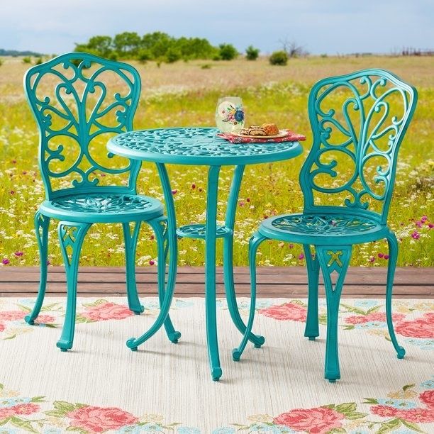The teal bistro set with a lattice pattern, complete with a plate and glass resting on the table.