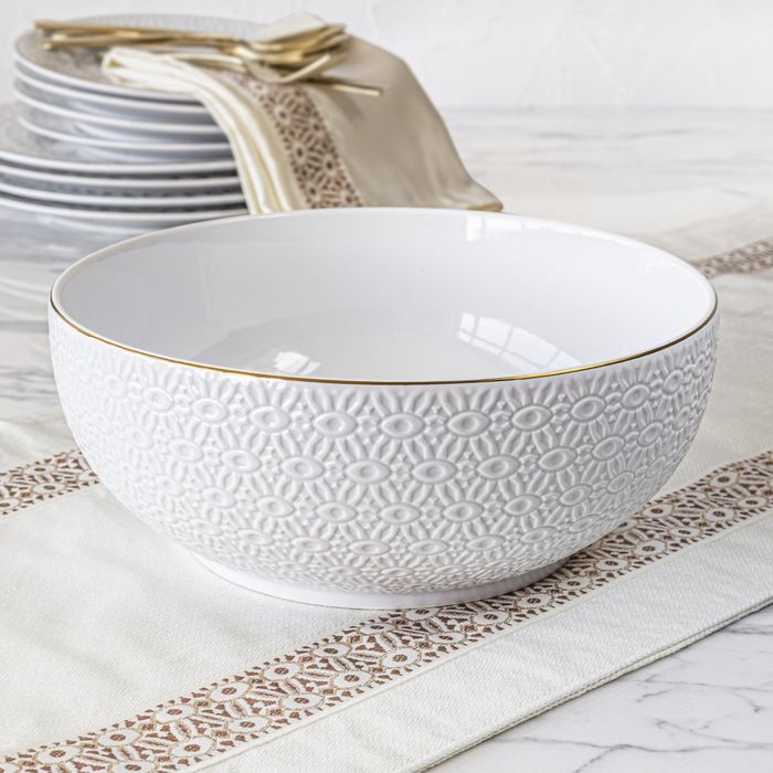 The white embossed serving bowl sitting beautifully on a table.