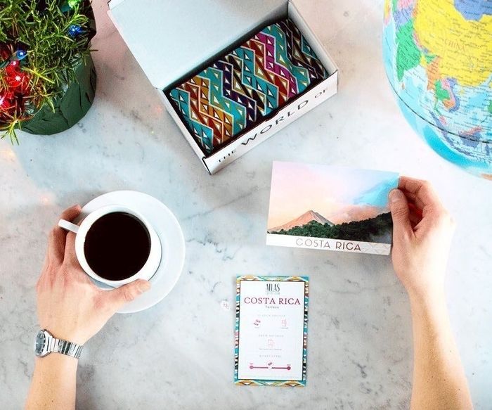 a cup of coffee placed beside a mug and a postcard