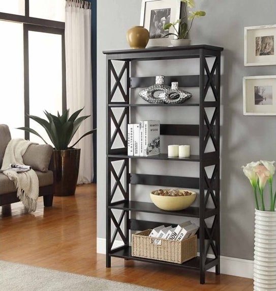 The black five-tier bookshelf filled with books, candles, and other decorative items.