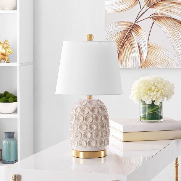 A table lamp with a white shade resting on a table.
