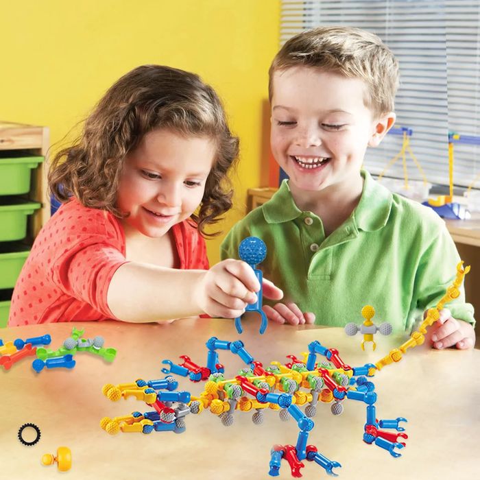 Two children happily constructing with a colorful building toy set on a table in a sunny room