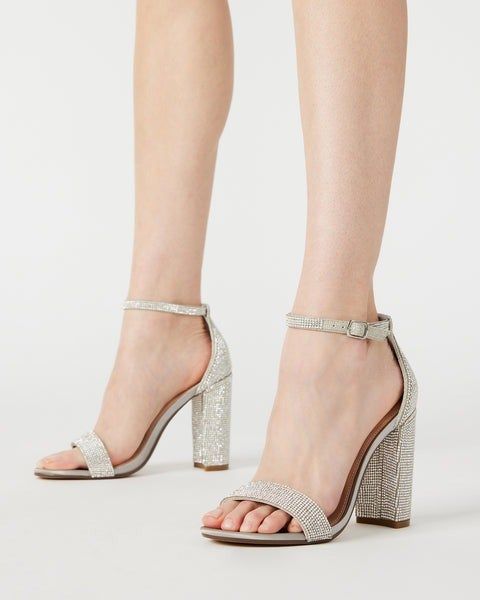A model showcasing silver rhinestone ankle-strap heels