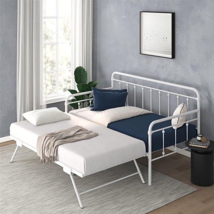 A daybed with a pull-out trundle in a contemporary room, featuring a white frame and navy accent pillows for a stylish touch.