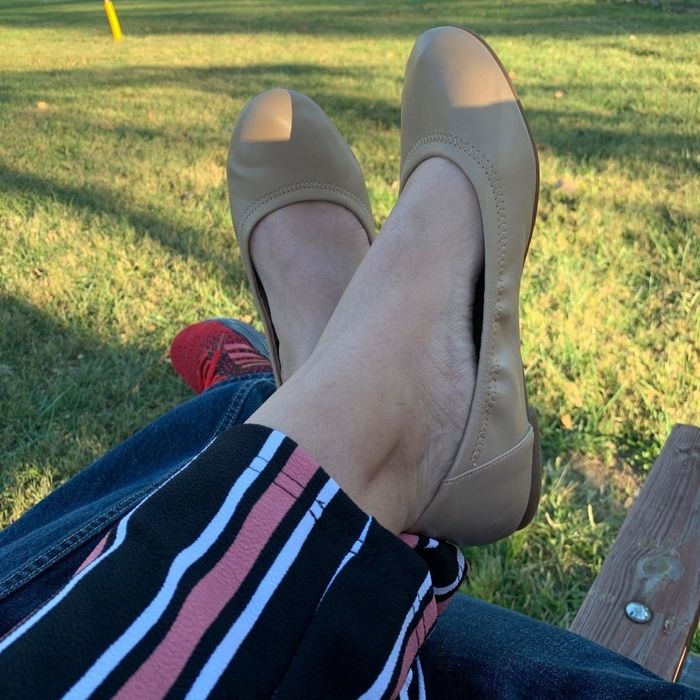 A photo of a reviewer dressed in striped pants and beige ballet flats.