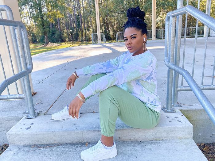 reviewer styling the white Puma sneakers with green joggers and a tie-dye long-sleeve shirt