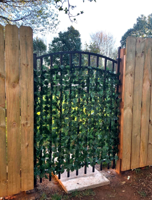 An iron gate adorned with faux ivy vines, covering the gaps and adding a touch of nature.