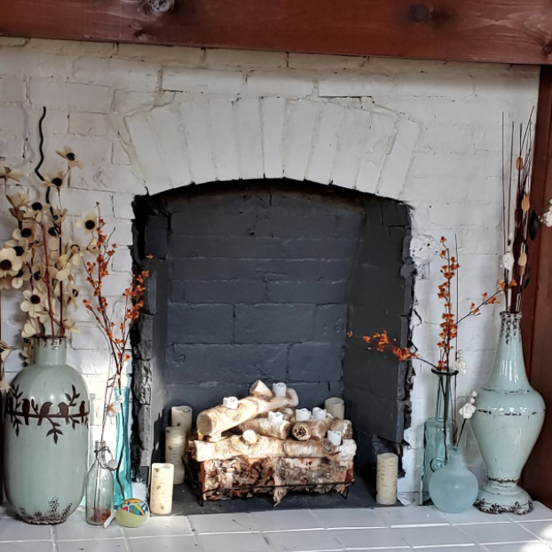 A reviewer's fireplace, beautifully styled with faux wood and tea light candles inside, creating a perfect cozy setting.