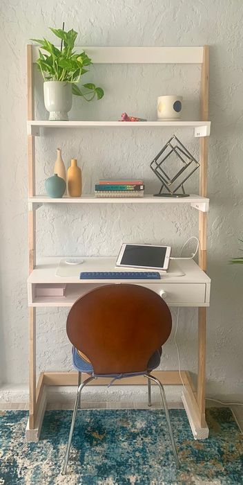 A home office arrangement featuring a desk, chair, shelving unit, and neatly organized decorative items and electronics
