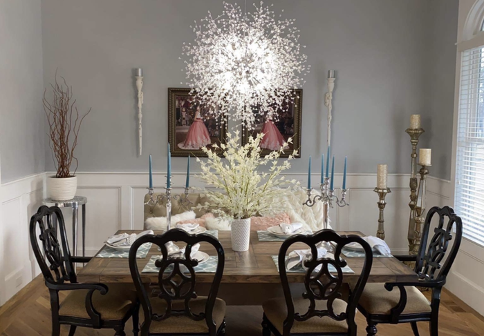 A dining room where the chandelier casts a cool glow above the dining table.
