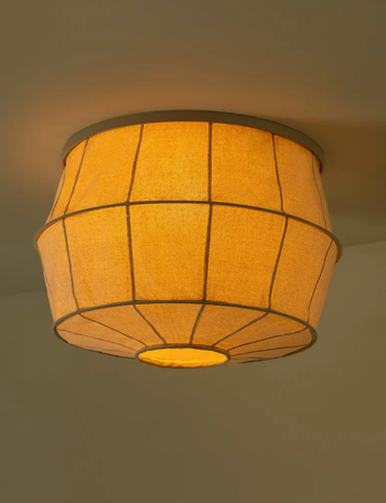 A ceiling light fixture featuring an illuminated fabric drum shade