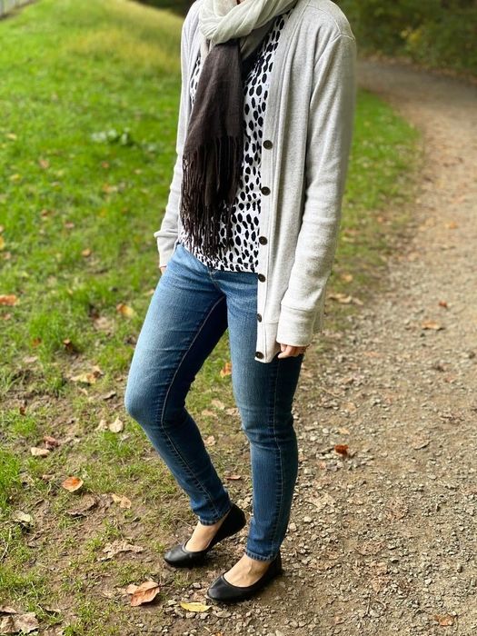 The reviewer is dressed in jeans and a cardigan, paired with basic black ballet flats.