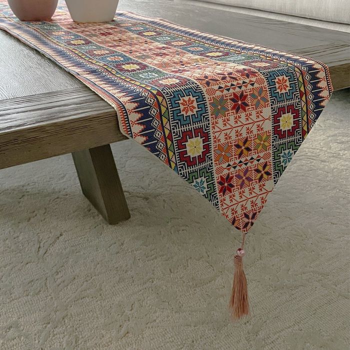 The table runner's end features a charming triangle shape with a tassel at the tip.